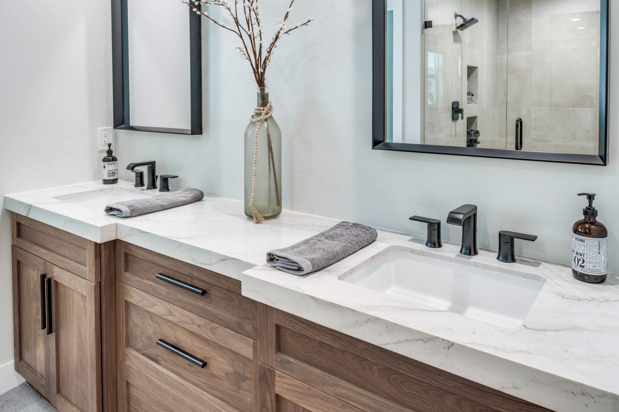 Remodeled bathroom with double vanity, stone counters, and walk-in shower