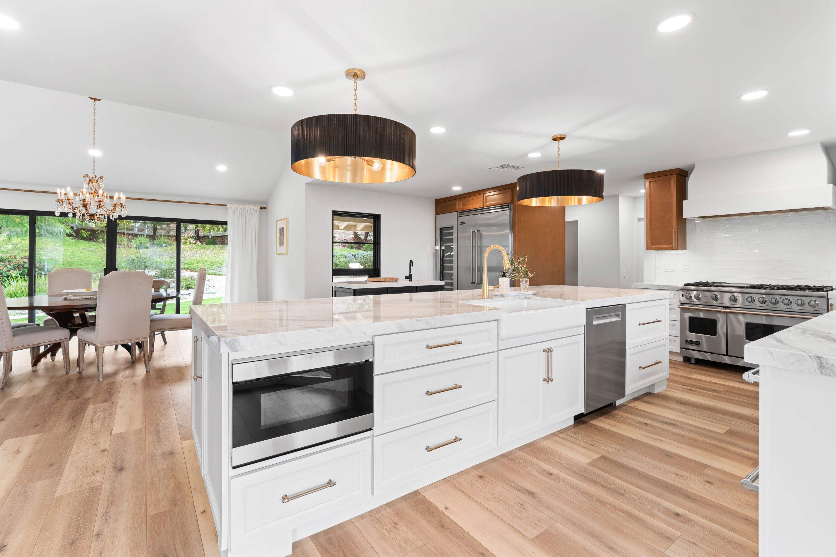 Finished white kitchen remodel with large island, gold fixtures, and dining area