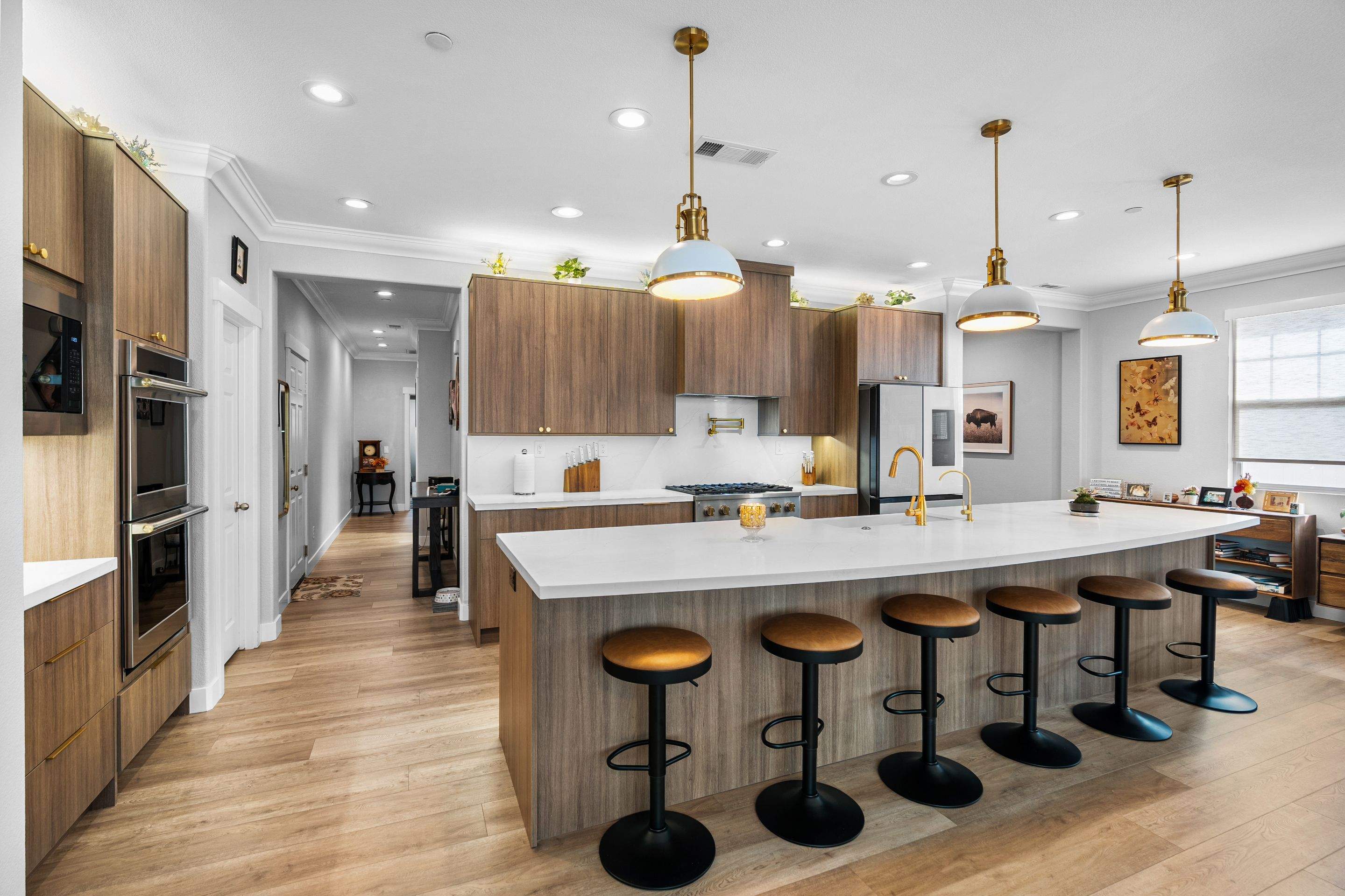 Finished kitchen remodel with walnut cabinetry, white island, and pendant lighting