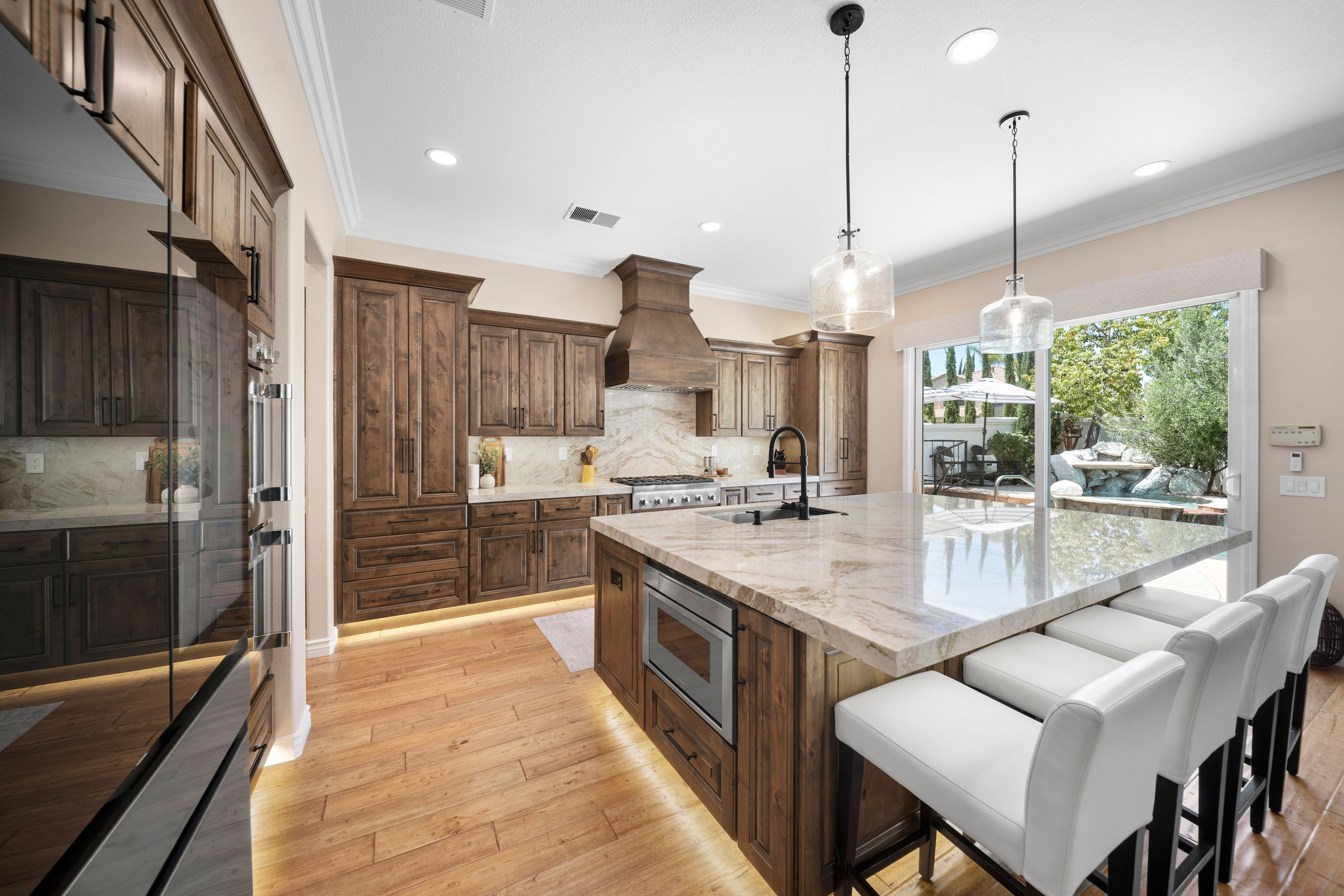 Kitchen remodel with walnut cabinetry, waterfall island, and backyard light